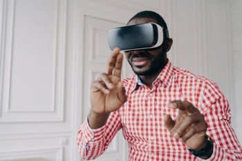 African man immersed in VR gaming at home, using virtual reality technology for business in modern office.