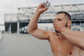 Athletic guy refreshes with water after intense workout, embraces sport, enjoys a healthy lifestyle.