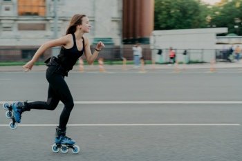 Energetic woman in motion, rollerblading on road. Blurred street background. Regular fitness activities for health and fitness