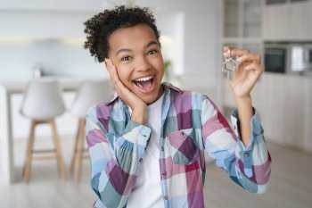 Ecstatic teen girl shows studio apartment keys, ready to move in.