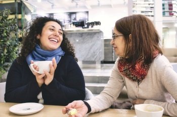 Two women of different generations having a good time enjoying a cup of coffee in a cafeteria