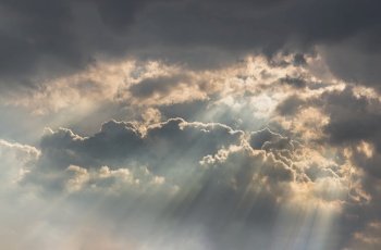 The sun’s rays passing through the clouds and shining form an interesting light pattern against the sky. Space for text, Selective focus.