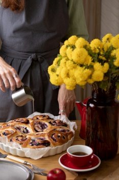 girl in an apron cooking in the kitchen cinnabon buns with cheese cream and  blueberries
