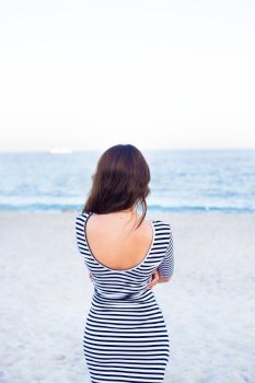 girl in a striped dress on the beach is back. girl in a striped dress on beach is back