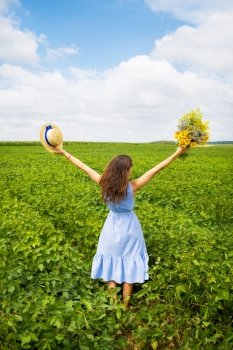 the girl is standing in the field with a bouquet of yellow flowers and a straw hat.. the girl is standing in the field with a bouquet of yellow flowers and a straw hat