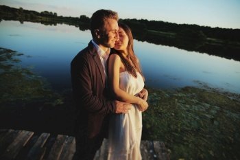 young couple in love are hugging outdoors near the lake at sunset on summer day. Romantic, love, people concept. love story.. young couple in love are hugging outdoors near the lake at sunset on summer day. Romantic, love, people concept. love story