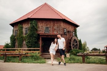 Couple in love walks near a large wooden mill on summer day. man and woman are having fun outdoors. Couple in love walks near a large wooden mill on summer day. man and woman are having fun outdoors.
