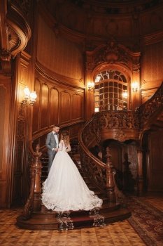 wedding day. beautiful bride in white long dress and young groom wearing in black suit are hugging inside big historic europe building. wedding day. beautiful bride in white long dress and young groom wearing in black suit are hugging inside big historic europe building.