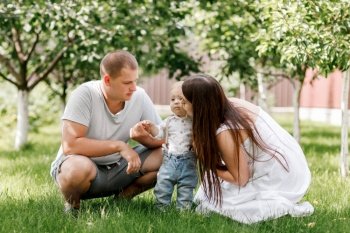Happy young family, mom, dad and baby son spending time together outdoors in summer green garden. mothers, fathers, babys day. Happy young family, mom, dad and baby son spending time together outdoors in summer green garden
