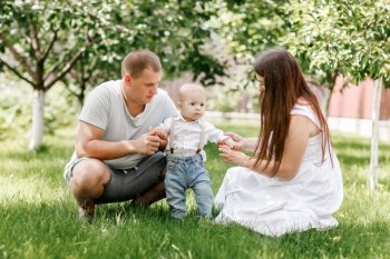 Happy young family, mom, dad and baby son spending time together outdoors in summer green garden. mothers, fathers, babys day. Happy young family, mom, dad and baby son spending time together outdoors in summer green garden
