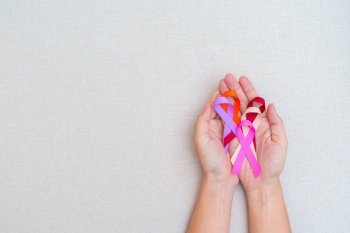 World cancer day, February 4. Hand holding burgundy, orange, pink, peach and purple ribbons for supporting people living and illness. Healthcare and medical concept