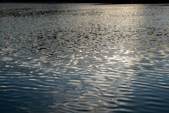 ?Beautiful Reflected the sun rays hitting the water surface river is waves the sea surface before sunset natural background.