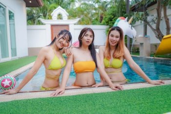 Asian three young sexy woman wearing a yellow bikini Playing in the pool at Pool Villa