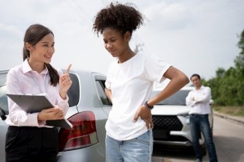 Women drivers Talk to Insurance Agent for examining damaged car and customer checks on the report claim form after an accident. Concept of insurance, advice auto repair shop and car traffic accidents.