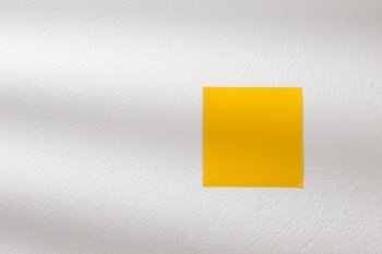 Yellow post it on the white wall