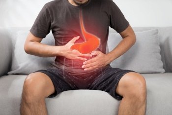 Acid reflux or Heartburn, The photo of stomach is on the men’s body against gray Background, Bad health, Male anatomy concept
