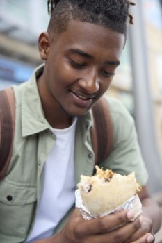 Young Man Eating Burrito At Outdoor Street Food Stall