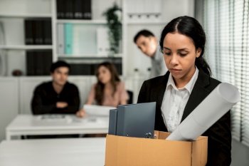 Depressed and disappointed employee packing her belongings after being fired for not being competent. Gossiped by her colleagues behind his back. Layoff due to economic depression.. Sad employee packing her belongings after being fired for not being competent.