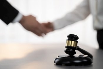 Focus gavel symbolize justice on blur background of lawyer colleagues handshake after successful legal deal for lawsuit to advocate resolves dispute in court ensuring trustworthy partner. Equilibrium. Focus gavel on blur background of lawyer colleagues handshake. Equilibrium