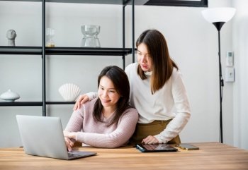 Asian middle age woman and teen they shoping online on computer, mother and teenage daughter looking at laptop computer at home office, happy family work together
