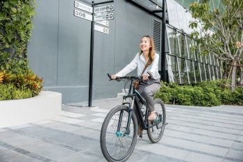 Asian beautiful young businesswoman with helmet riding bicycle go to office work at city street with bicycle in morning, Happy lifestyle woman bike after business work outside building , Eco friendly