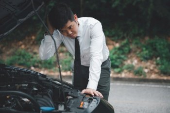 Asian businessman car broken breakdown, angry young stressed man stands trouble car failure problem looking in frustration at failed engine in morning, accident on road outdoor, late for business work