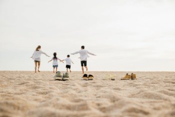 Happy family day. lifestyle father, mother and kids take off shoes running on sand, Back view Asian having family parents with child fun holding hands together run to beach, tropical summer vacations