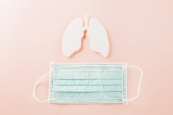 World Tuberculosis Day. Overhead lungs paper symbol and facial medical face mask on pink background, lung cancer awareness, copy space concept of world TB day, banner background, pneumonia awareness