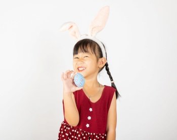 Happy Easter Day. Smile Asian little girl wearing easter bunny ears holding colorfull eggs on hands isolated on white background with copy space, Happy child in holiday