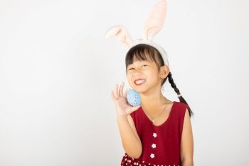 Happy Easter Day. Smile Asian little girl wearing easter bunny ears holding colorfull eggs on hands isolated on white background with copy space, Happy child in holiday