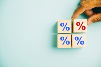 The concept of interest rate and mortgage rates. Businessman’s hand positioning a wood cube block with a percentage symbol icon, emphasizing the ever-changing nature of rates.