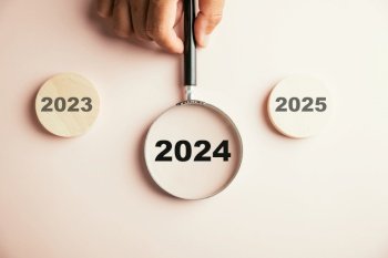 A magnifier focused on the 2024 icon, emphasizing the target business for upcoming year. It symbolizes planning, innovation, investment ideas transitioning from end of 2023 to the new year concept.