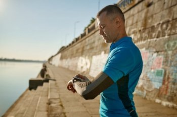 Runner checking smartwatch controlling pulsations after exercise. Sport and fitness, healthy running concept. Runner checking smartwatch controlling pulsations after exercise
