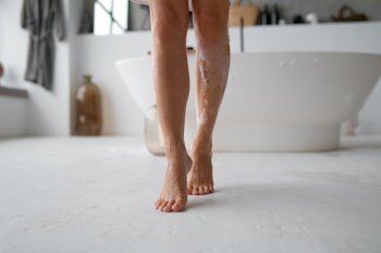 Low section view of barefoot female wet foamy feet stepping on bathroom floor. Morning hygiene routine. Low section view of female wet foamy feet on bathroom floor