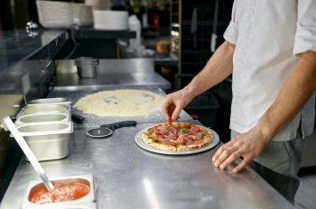 Pizzaiolo making pizza at kitchen with closeup focus on hand. Italian pastry preparation for delicious lunch or dinner. Pizzaiolo making pizza at kitchen with closeup focus on hand