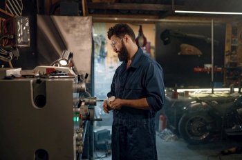 Repairman supervising work on lathe and inspecting motorcycle vehicle part operating process. Mechanic in garage workshop concept. Repairman supervising work on lathe and inspecting vehicle part