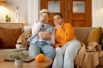 Young lesbian woman couple watching scary movie on tv spending time at home. Young lesbian woman couple watching scary movie at home