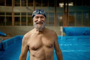 Portrait of smiling senior man with wet body in swimming pool at gym. Happy smiling athlete elderly male swimmer feeling satisfied after training looking at camera. Portrait of smiling senior man with wet body in swimming pool looking at camera