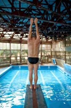 Back side view on strong senior man swimmer starting diving jump in swimming pool. Training class for retired people. Back side view on strong senior man swimmer starting diving jump in pool
