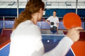 Two young woman holding racket kicking ball playing table tennis practicing before tournament. Selective focus. Two young woman playing table tennis practicing before tournament