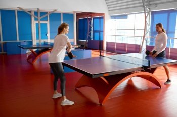 Man and woman playing table tennis indoors. Male instructor teaching female student at professional sport club. Man and woman playing table tennis indoors