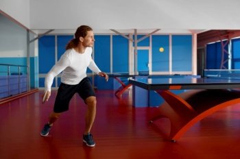 Young man table tennis player kicking ball with racket in motion. Professional sport and active lifestyle concept. Young man table tennis player kicking ball with racket in motion