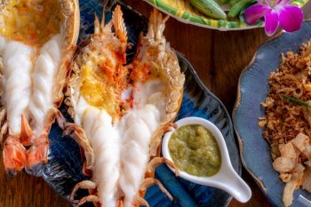 Grilled giant river prawn in a Thai luxury restaurant. Seafood in Thailand. Grilled giant river prawn served on a plate with Thai seafood sauce. Thai cuisine. Grilled giant shrimp on a dinner table.
