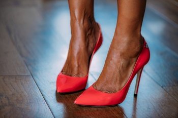 Woman putting on red high heeled shoes.. Red high heels