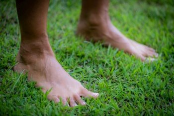 Grounding practice, barefoot woman standing on the grass.. Grounding or earthing practice