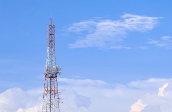 Large Communication telecom tower with antenna against white clouds on blue sky background