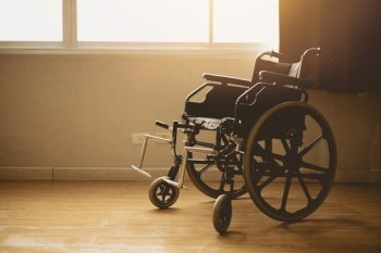 wheelchair in hospital room at windows morning sun light