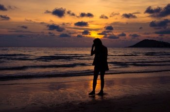 silhouette girl walking on beach with sunset