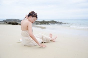 asian women sitting on sea beach and touch her hair