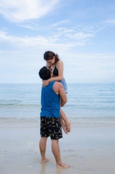 asian couple standing on beach, with man holding girl